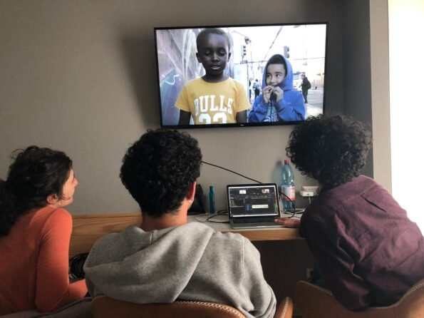 Tres jóvenes viendo una muestra audiovisual del Festival en la televisión